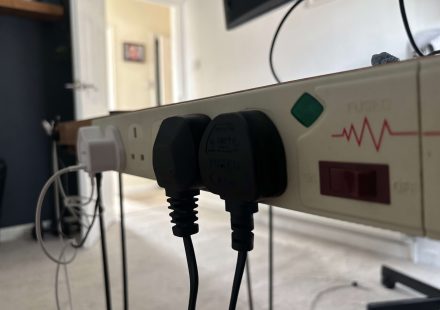 Surge protector mounted to the back of a desk.