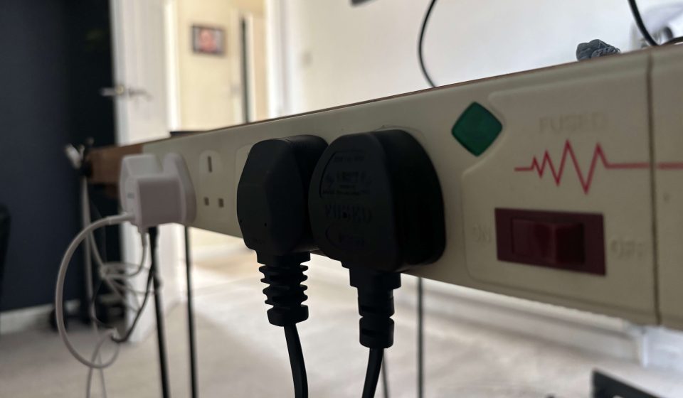 Surge protector mounted to the back of a desk.